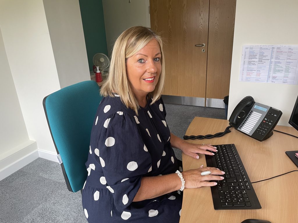 Mandy Director of Clinical and Patient Services, sat at desk typing
